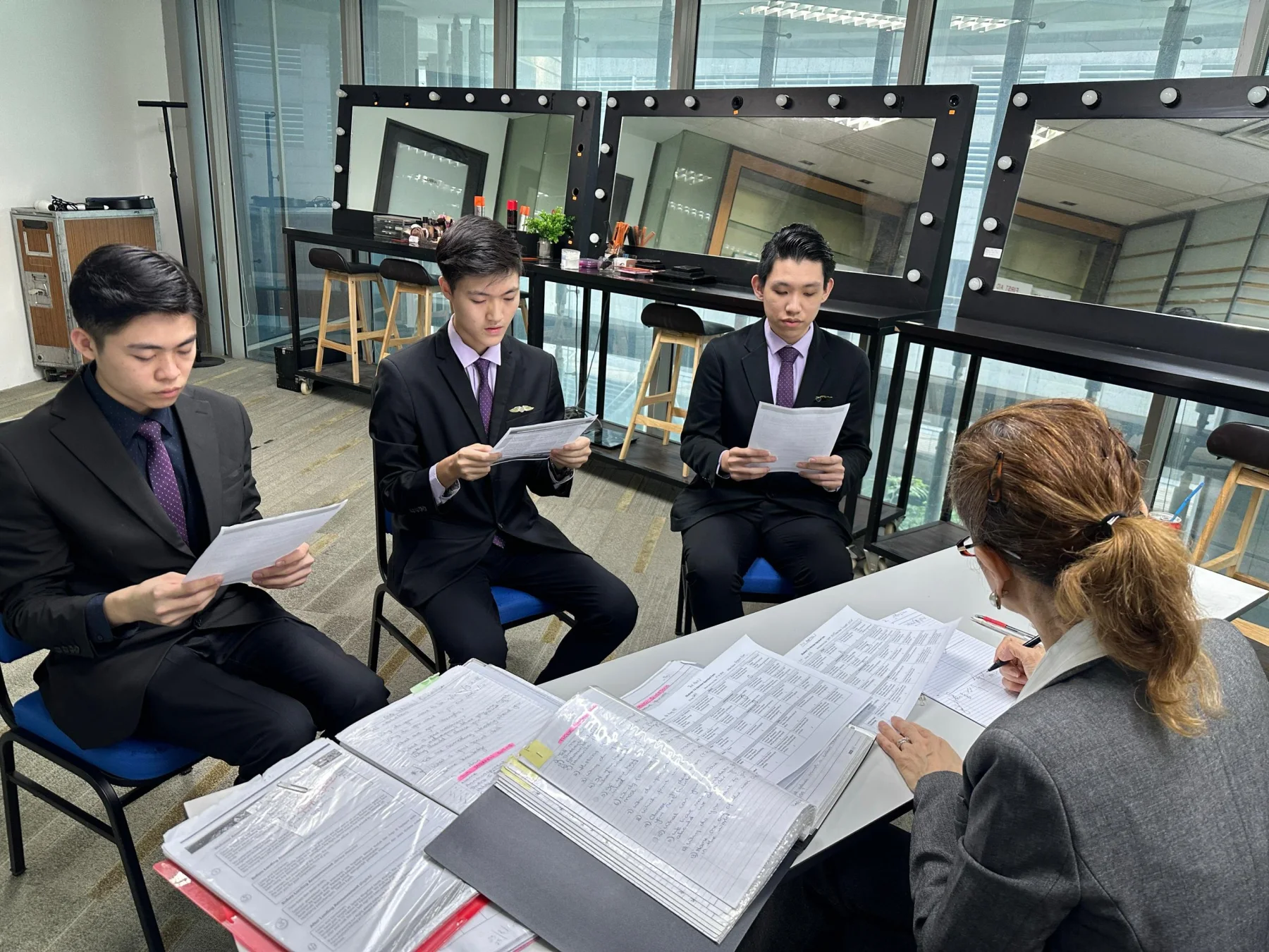 Two students taking part in a seated mock interview with a trainer