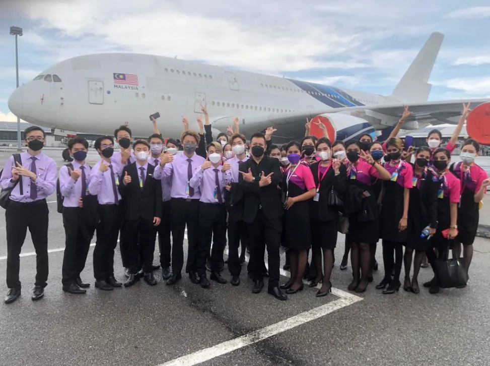 Students in coordinated uniforms posing in front of a commercial aircraft