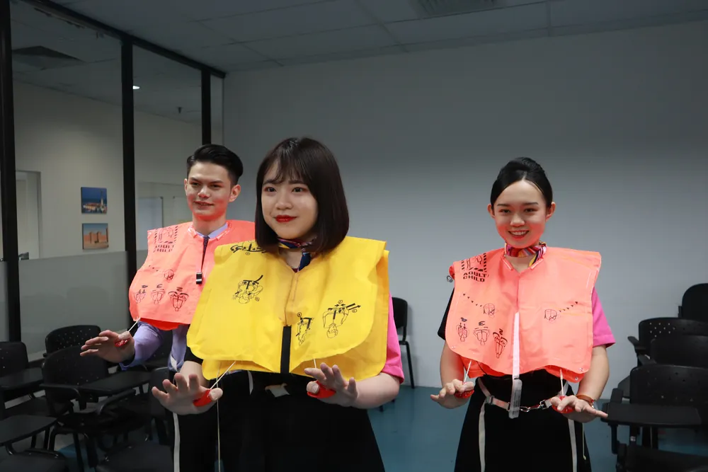 Trainees demonstrating cabin safety equipment with life vests in the classroom