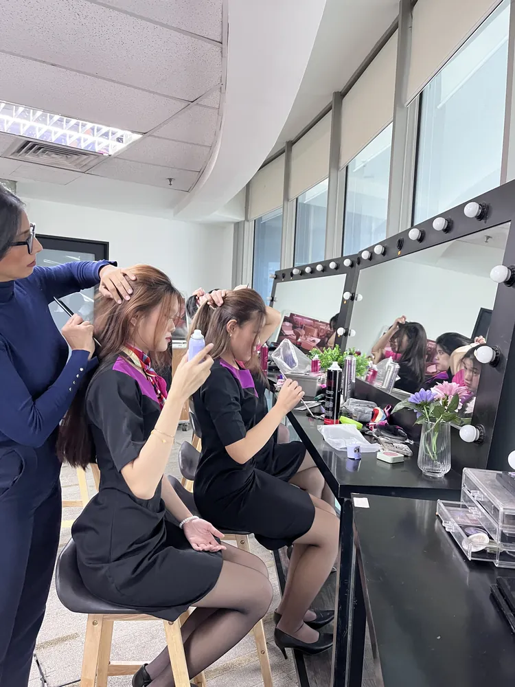 Students in uniform practising grooming and presentation in the academy salon