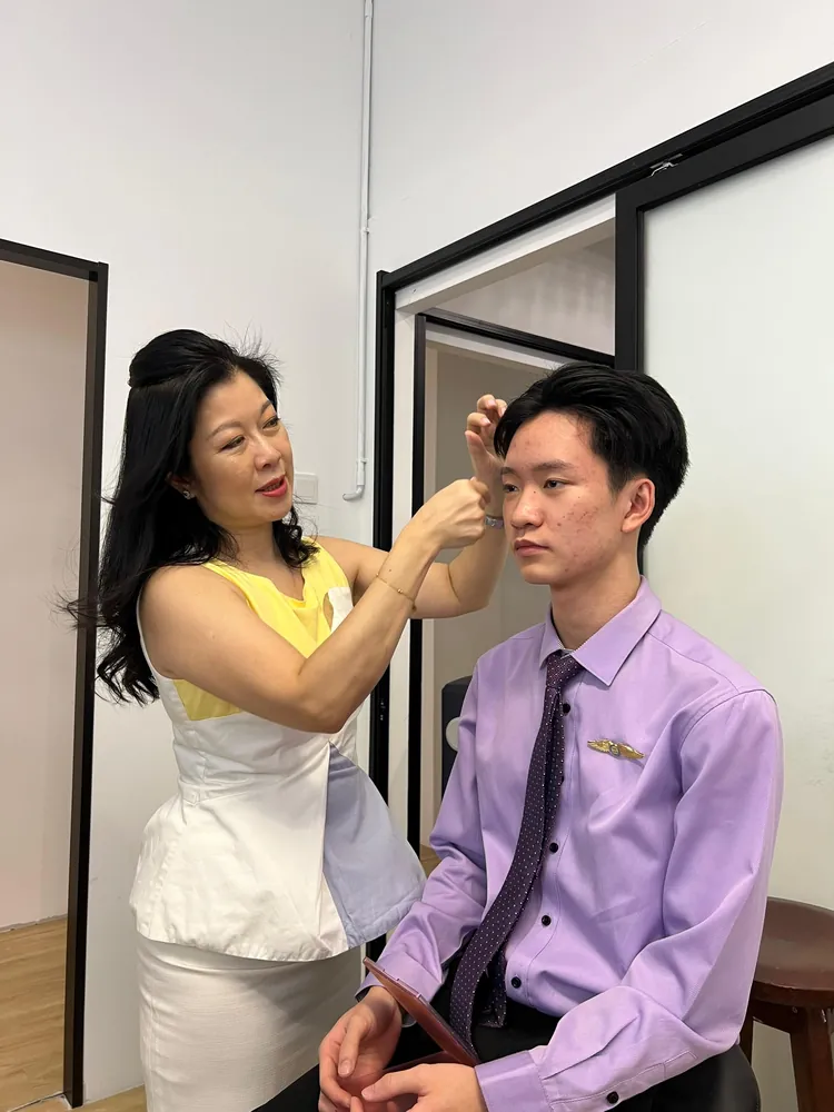 A trainer adjusting a student's presentation during a grooming session