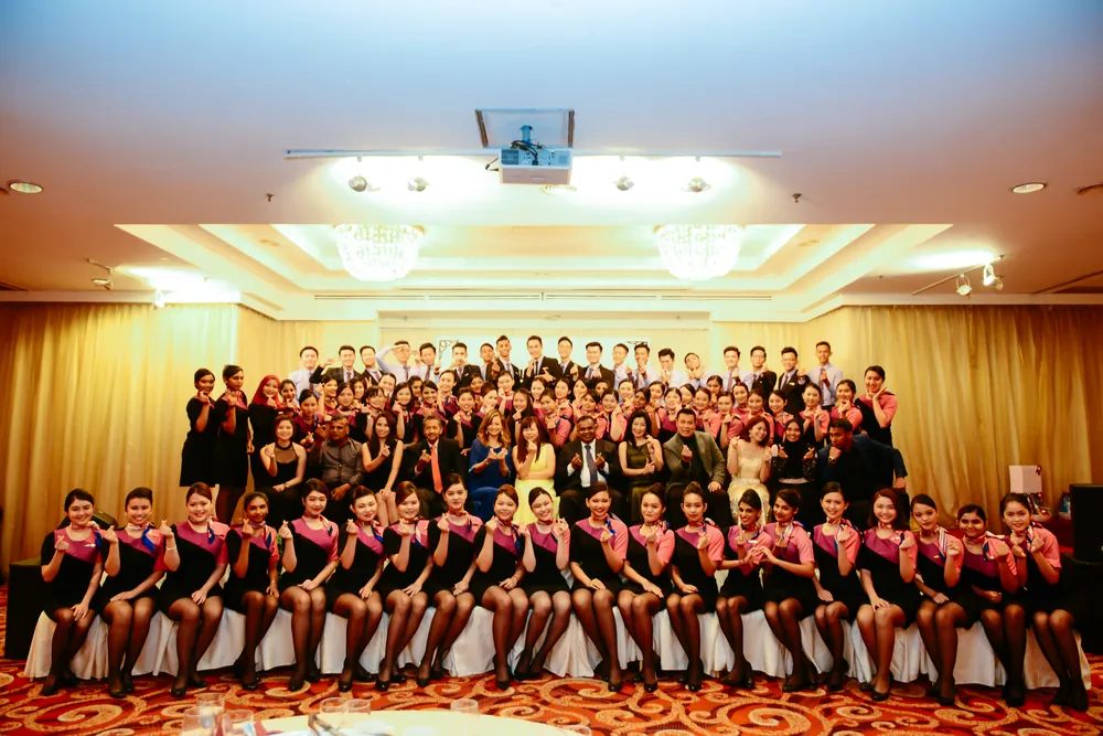 Graduates and guests in matching uniforms posing for a group photo at the Inter Excel graduation dinner